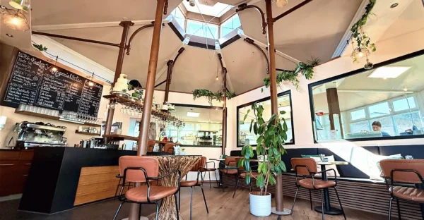 Gemütlicher Thekenbereich und Kaffeebar im Café der Tortenfee in Alling mit Blick auf die Kuchentheke, Menütafel und stilvolle Sitzplätze unter dem großen Dachfenster.